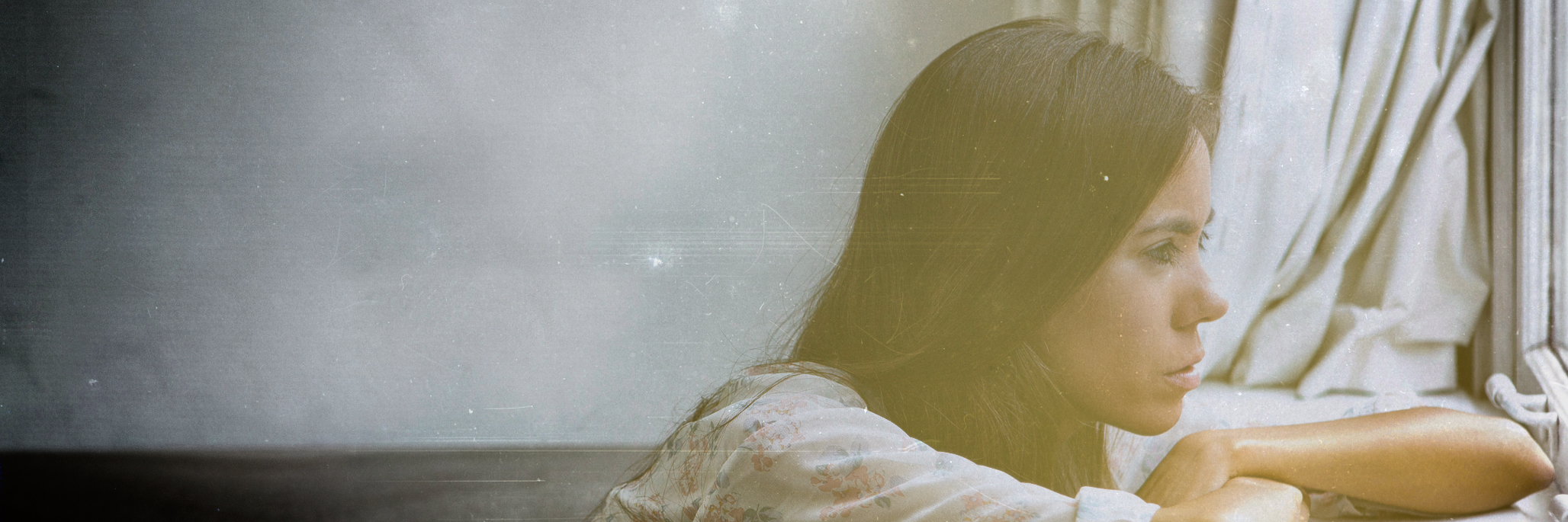 Finding Meaning When You're Housebound With Epilepsy Woman sitting alone looking out window.