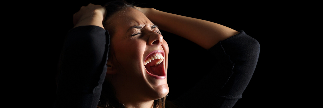 When Anxiety Triggers Explosive Anger Depressed woman crying and shouting desperately isolated in a black background