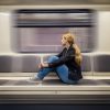 A blonde woman sitting in subway train and looking at window.