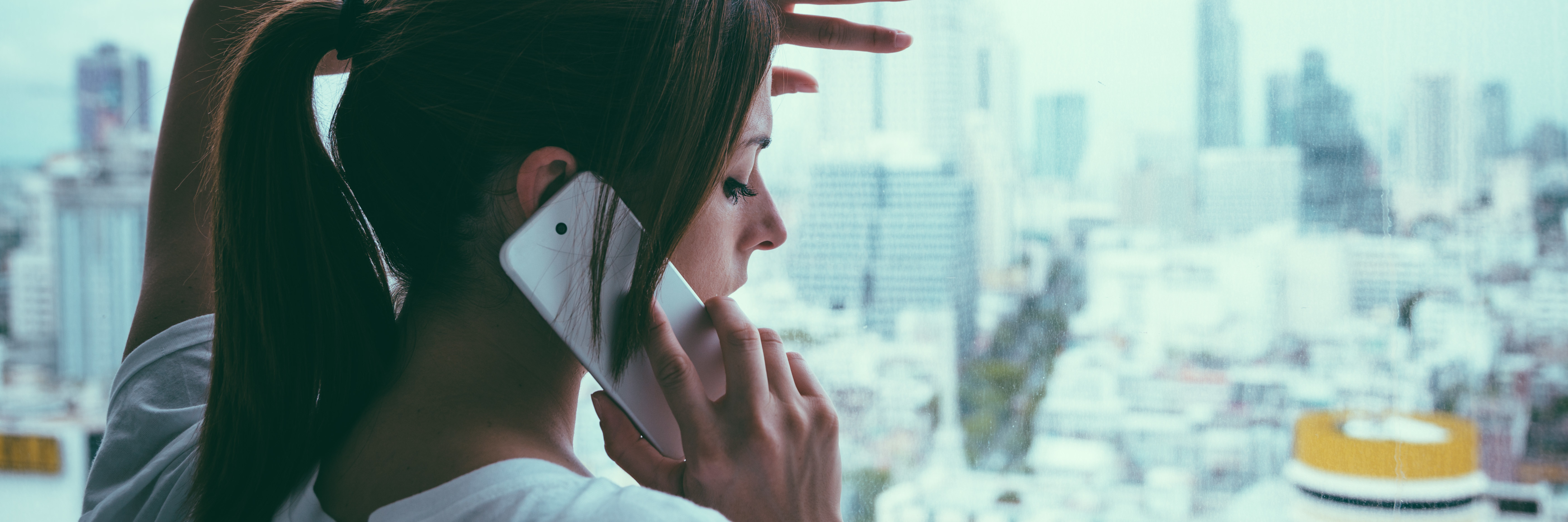 My Experience With Suicide and Calling a Crisis Line woman on phone standing at window looking out at gray sky