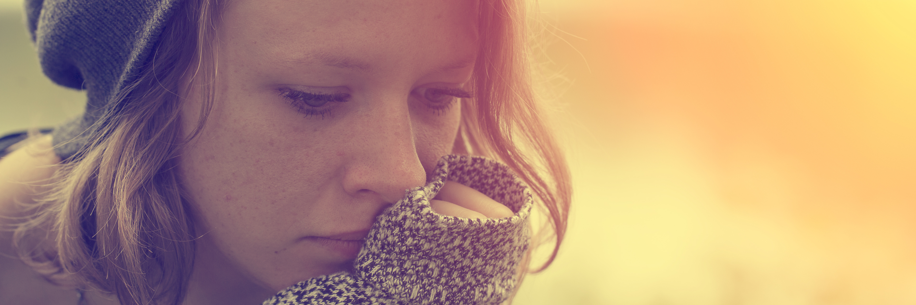 What It Means When I Say I'm Sorry for Depression and Anxiety young woman wearing hat sitting outside with chin resting on palm feeling alone