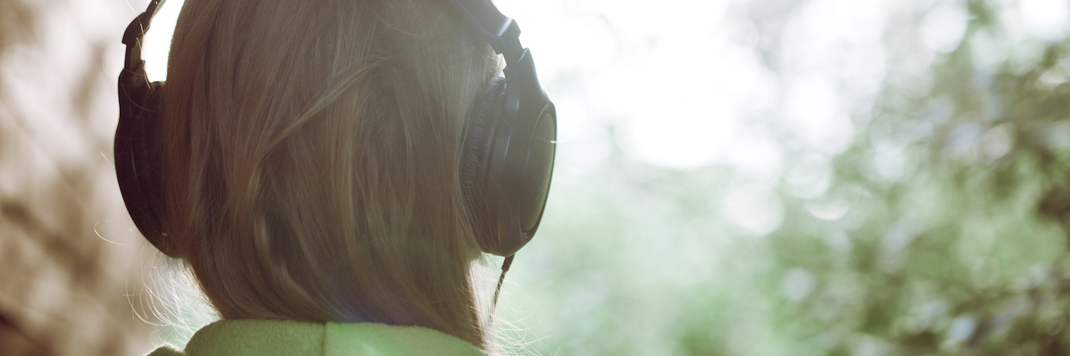 The Sound of My Grief: How Music Helps Me Heal Woman wearing headphones, outdoors facing trees