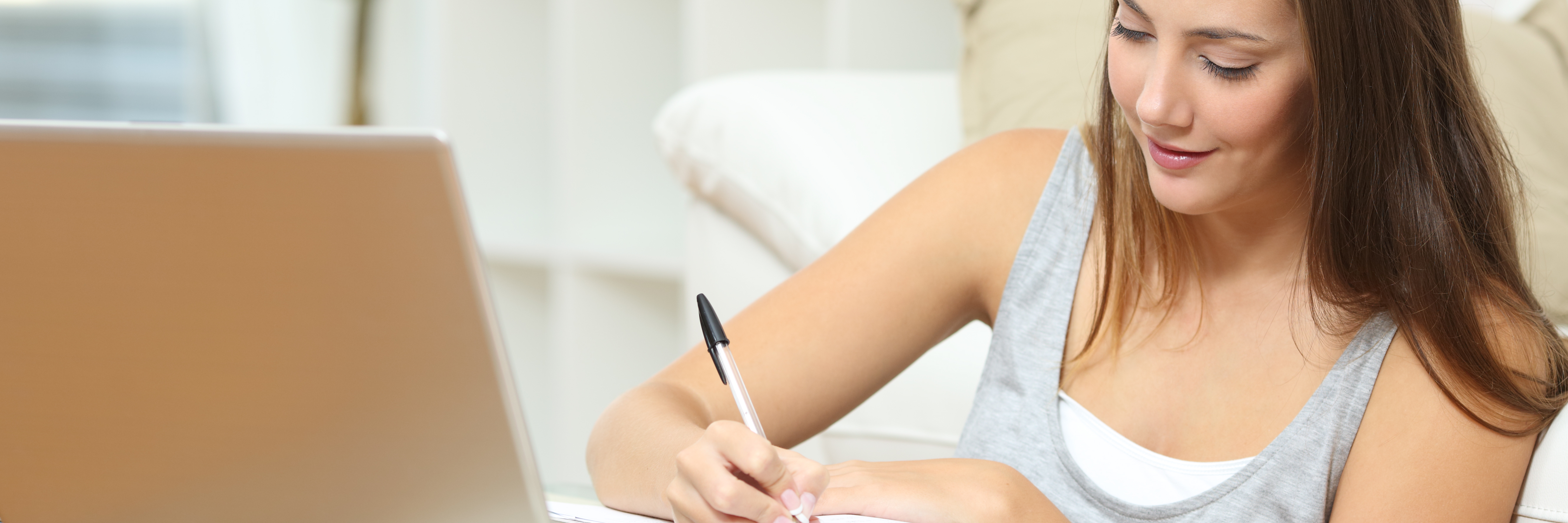 young woman with notebook and laptop writing at home