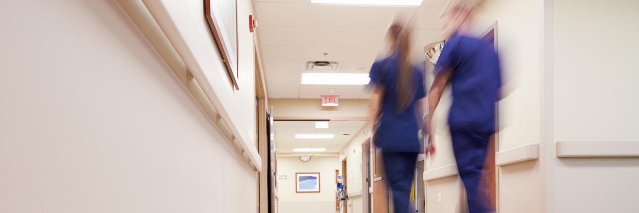 two nurses blurred walking down hospital corridor