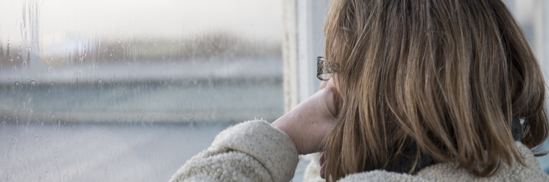Not Wanting to Leave Home Due to Anxiety and Chronic Illness woman staring out the window on a rainy day
