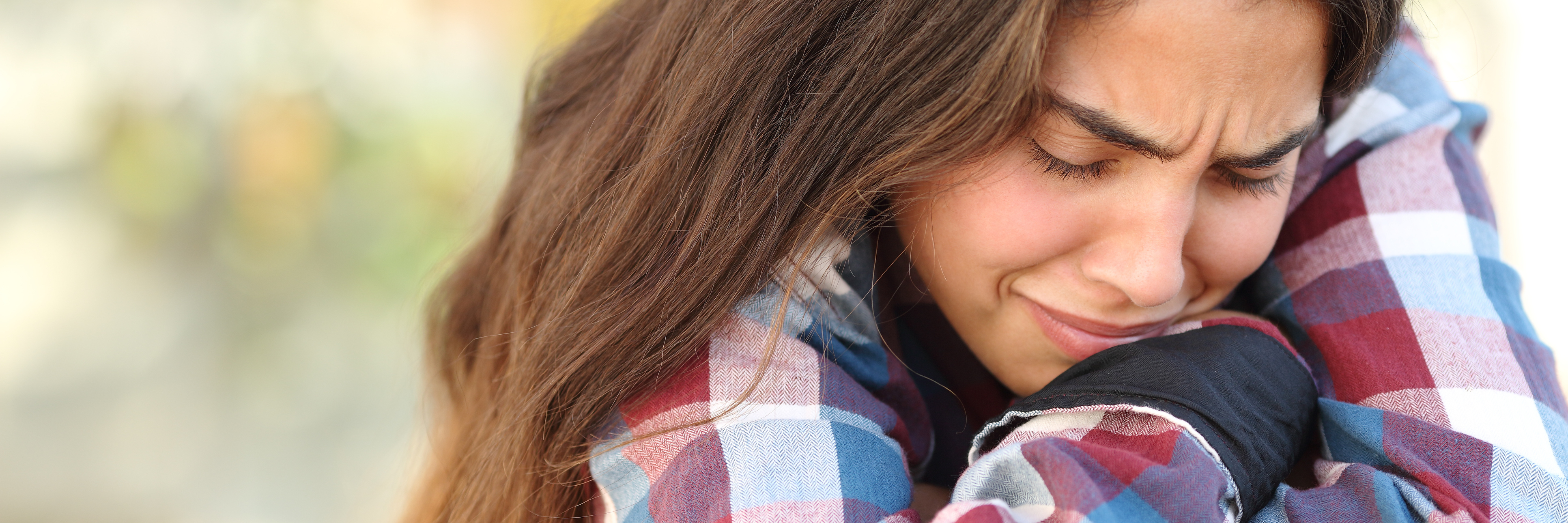 The Truth About How My Depression and Anxiety Affect My Studies young woman crying outdoors hugging knees