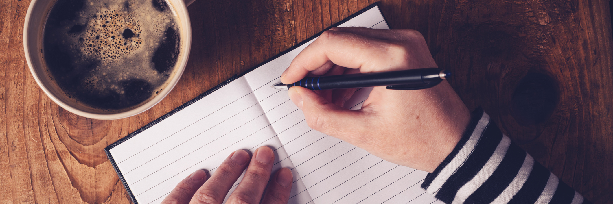 Why Poetry Is the Perfect Coping Mechanism for My Anxiety Woman drinking coffee and making a diary note, top view of female hands writing in notebook, retro toned image with selective focus.