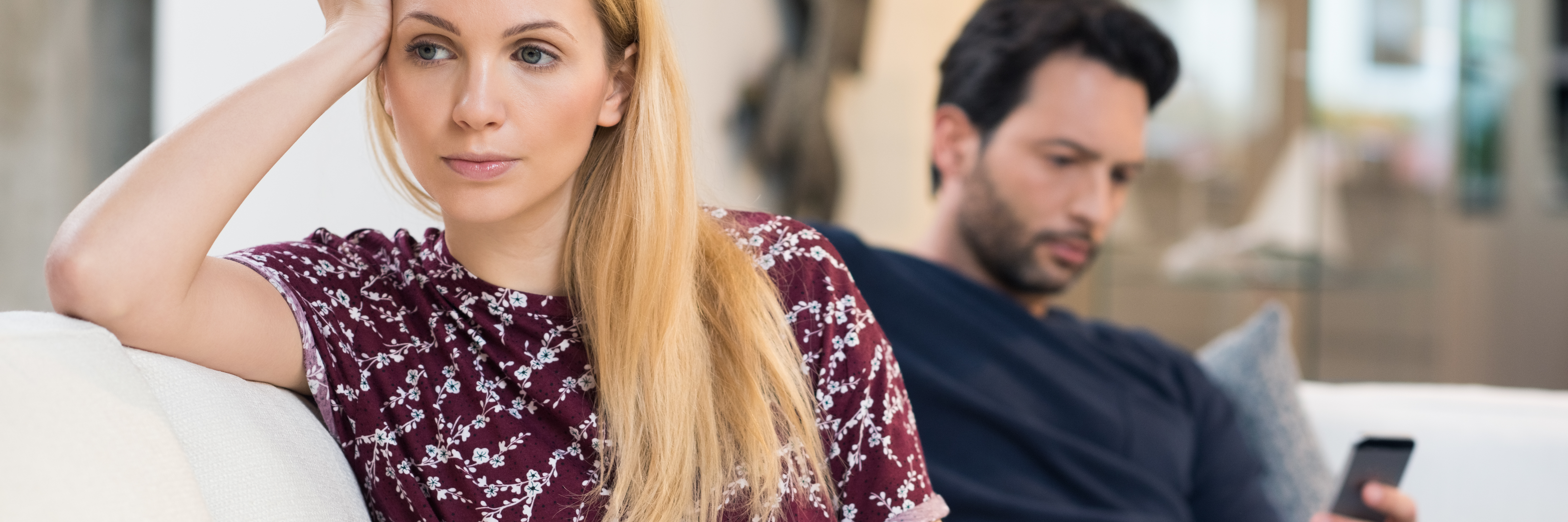Why Good Listening Is Important in Mental Illness Support young couple on sofa with man on phone and woman facing away head resting on hand not speaking