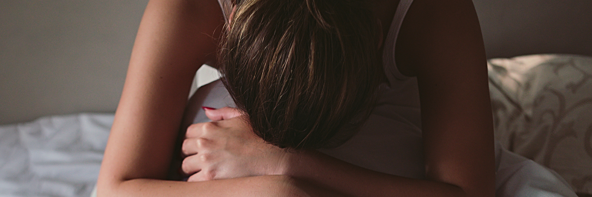 young woman in bed with head on knees