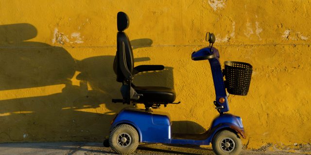 4 Reasons a Mobility Scooter Means Freedom Blue scooter against yellow wall.