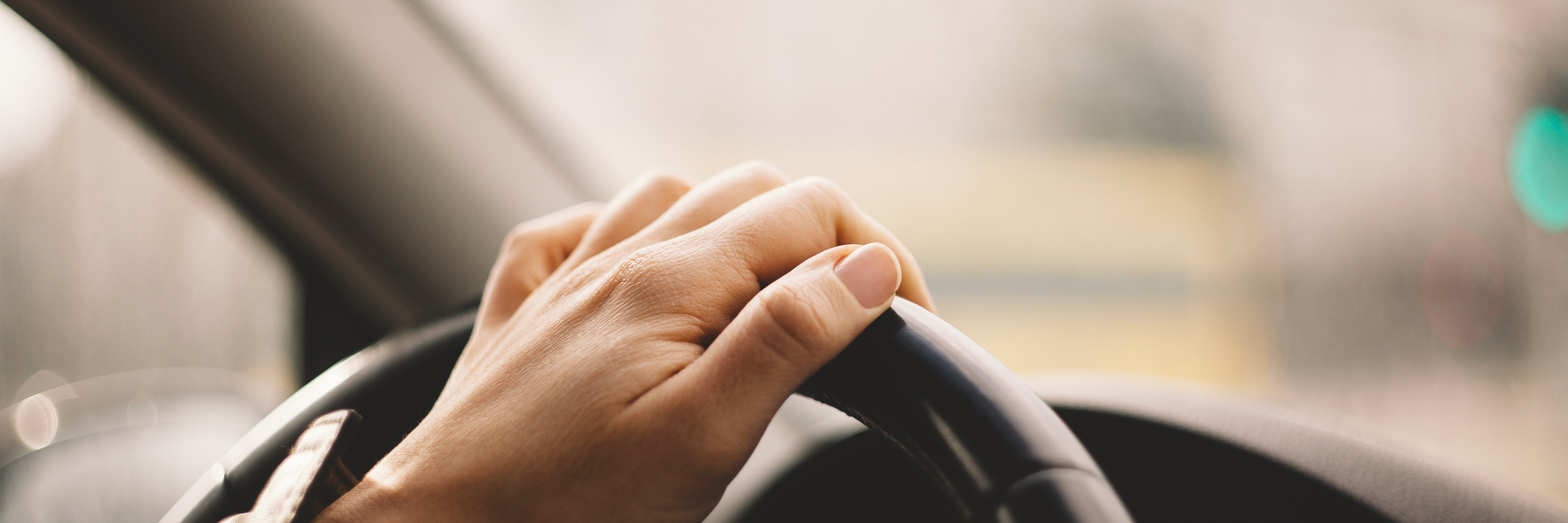 Close-up of a woman's hand driving a car.