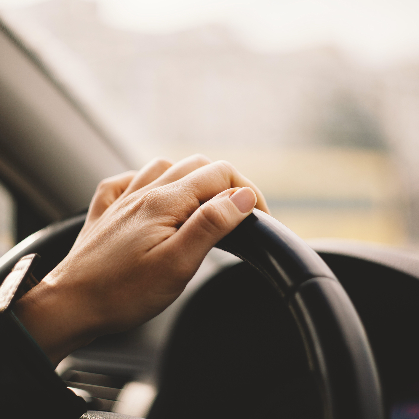 Close-up of a woman's hand driving a car.