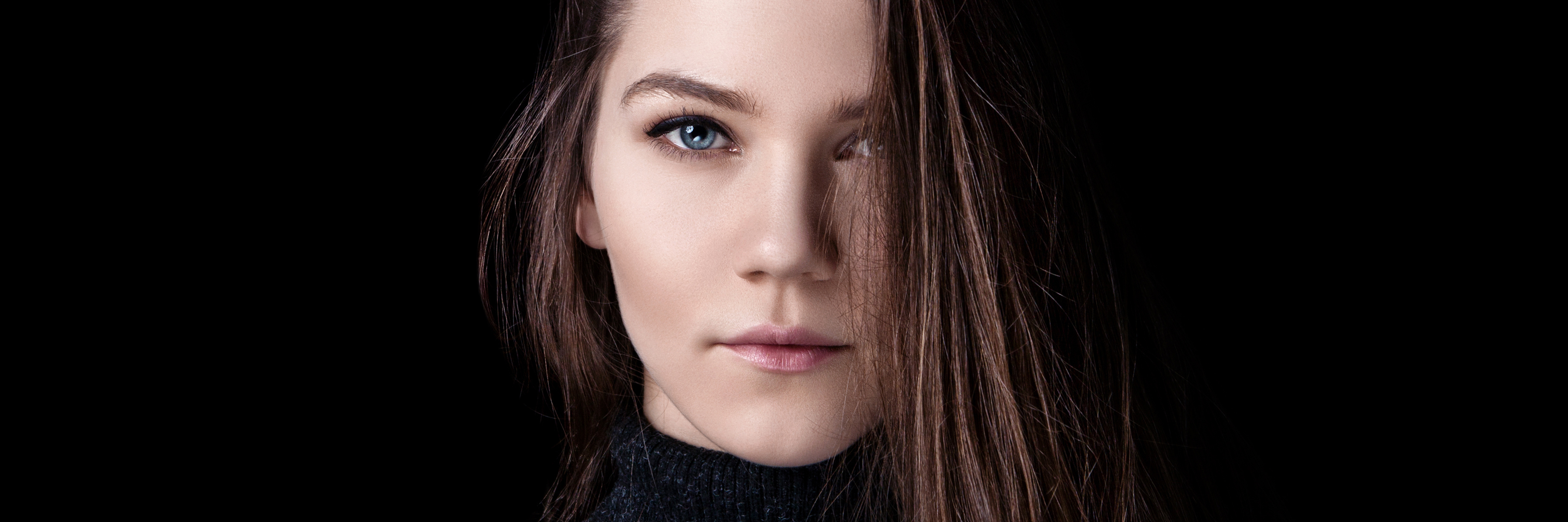Being on Disability Does Not Mean I'm 'Lazy' or 'Lucky' Portrait of a young woman with brown hair, against a black backdrop.