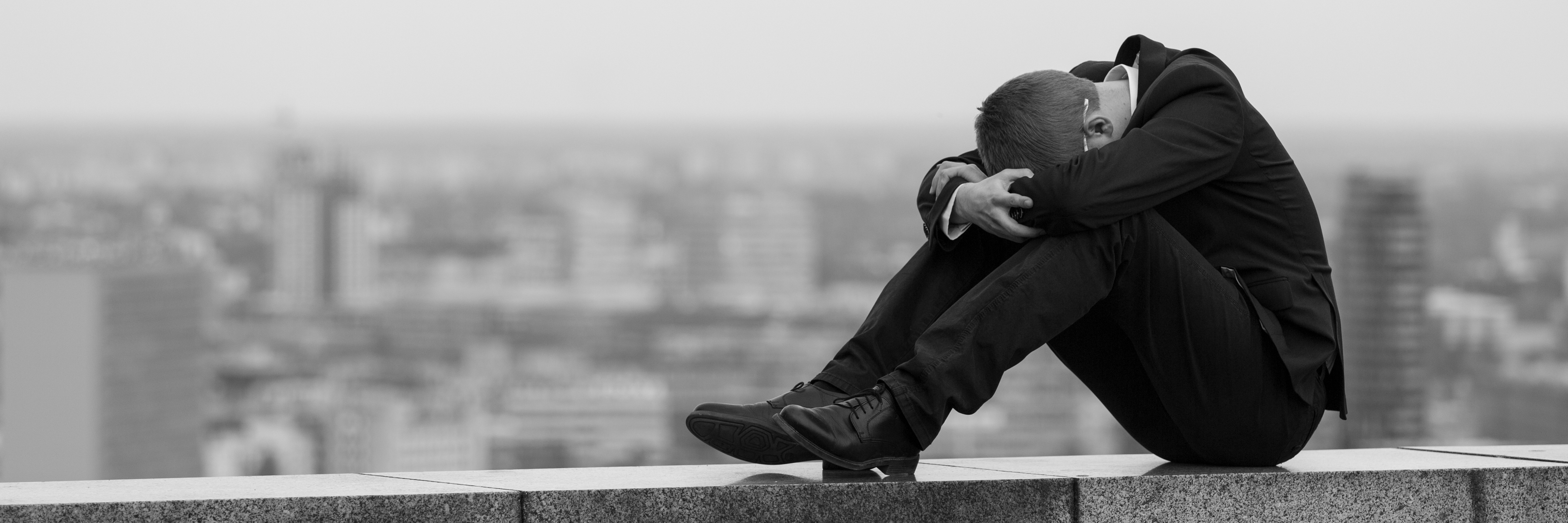 young man sitting on edge of room with depression