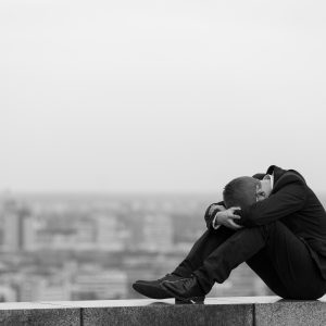 young man sitting on edge of room with depression