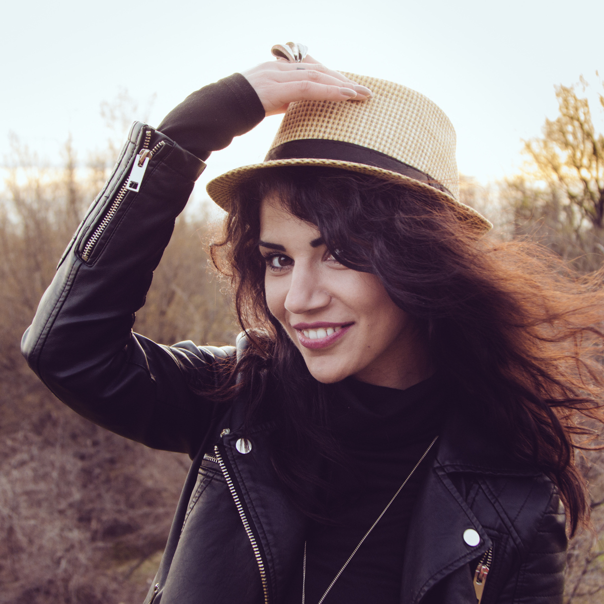 A brunette woman wearing a hat outdoors.