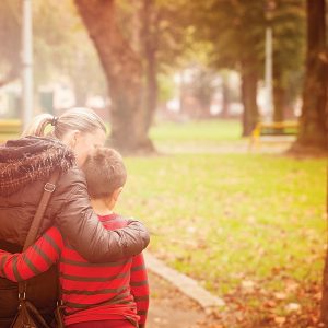 woman hugging son and walking in park