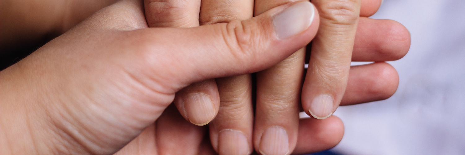 Two people holding hands in comforting gesture