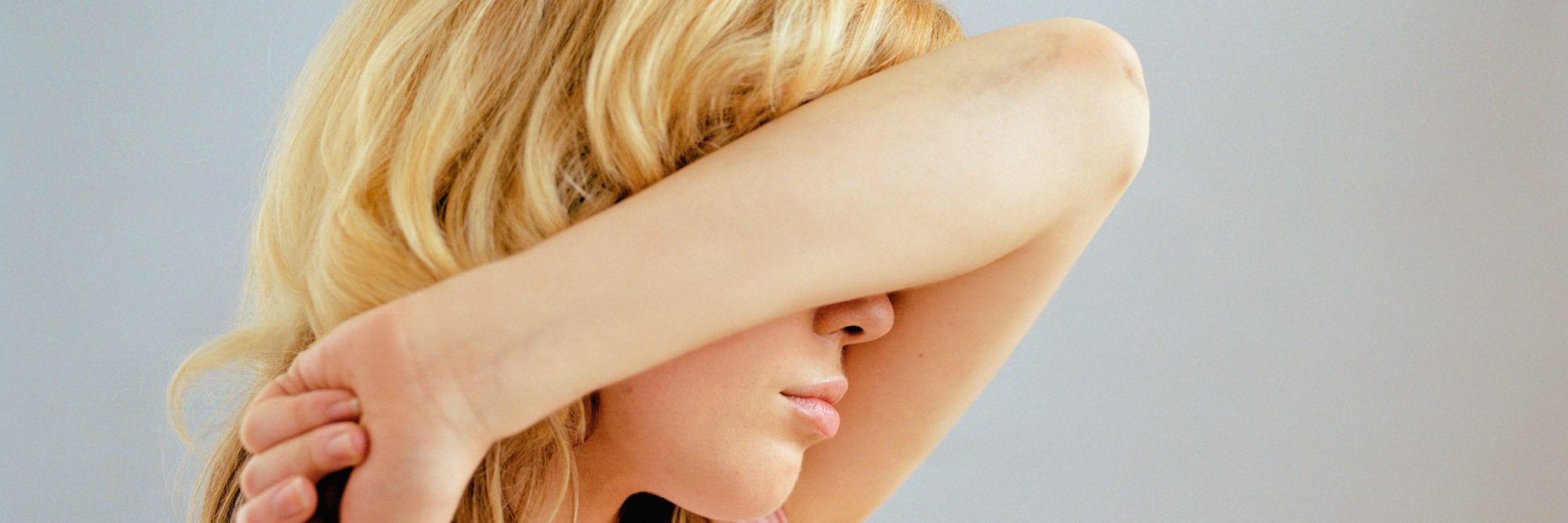 The Difference Between Perfectionism and OCD blonde woman covering face with arm