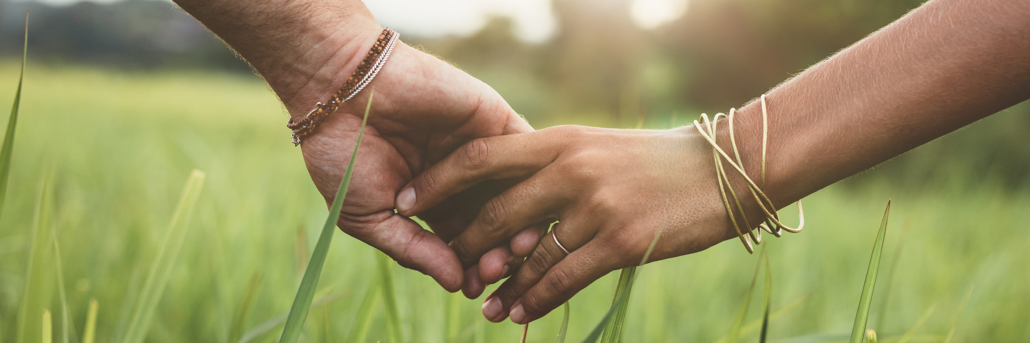 To My Husband, Who Has Only Known Me in Remission Man and wife holding hands, walking in a grassy field.
