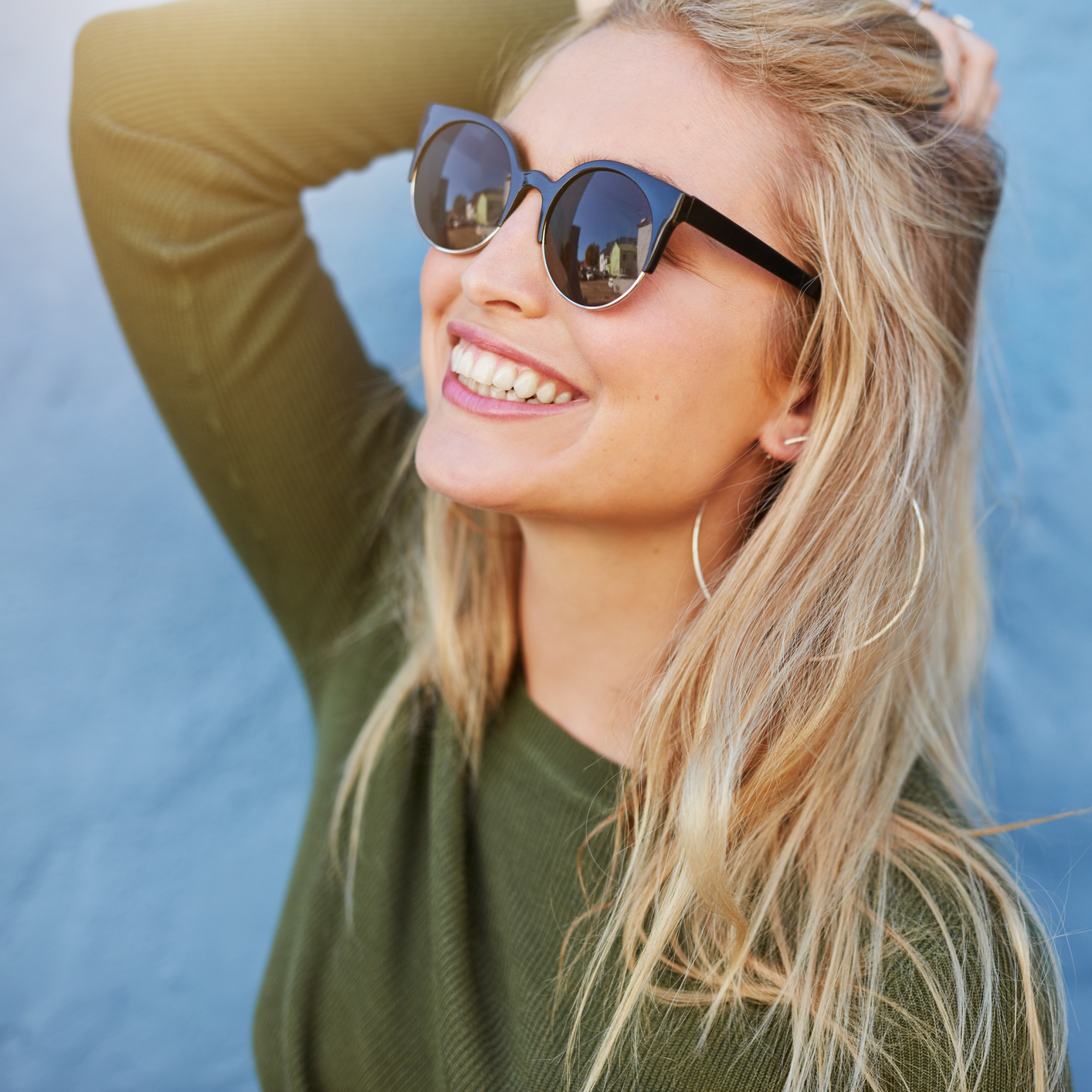 A woman wearing sunglasses, smiling.