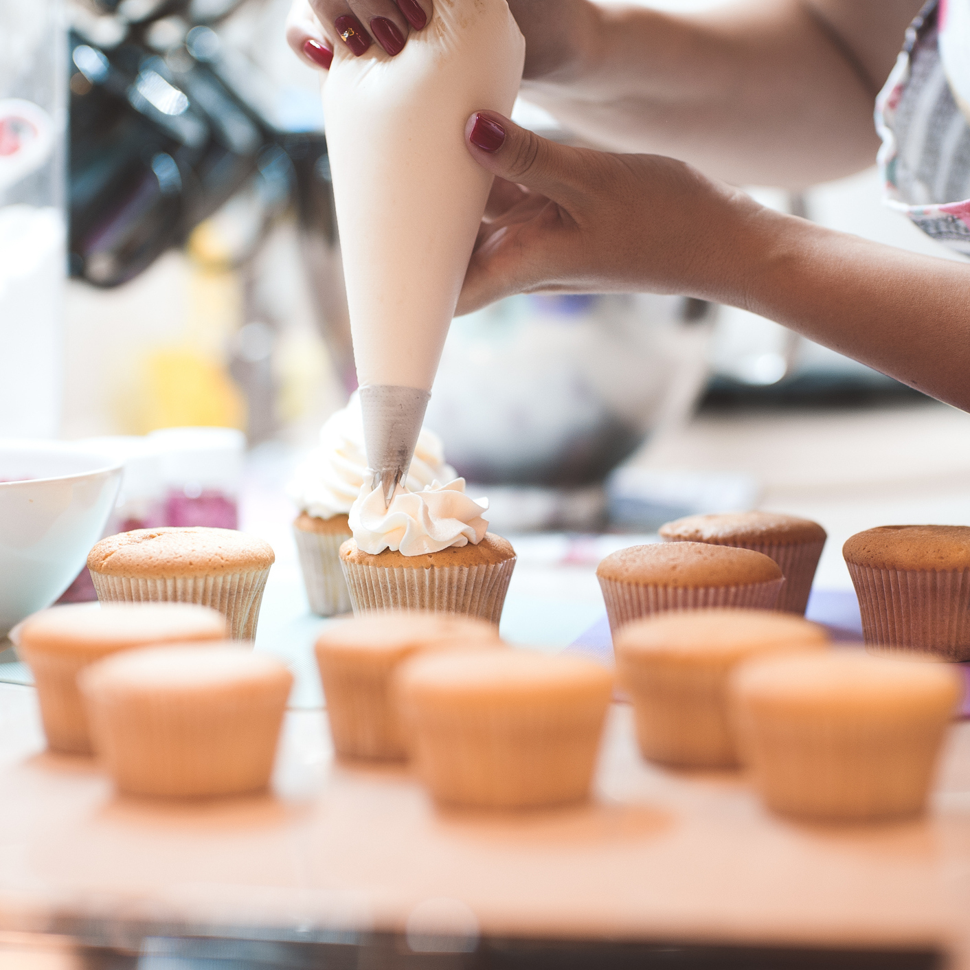 woman frosting a batch of cupcakes