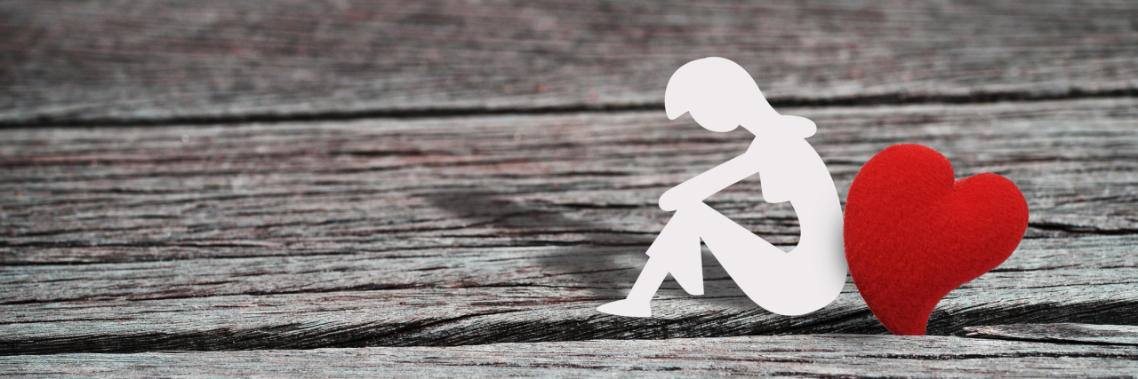 Borderline Personality Disorder and Loving Too Much, Too Deeply paper woman leaning against red heart on wooden floor