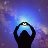 Silhouette of woman making heart shape with hands, with arms extended toward starry night sky