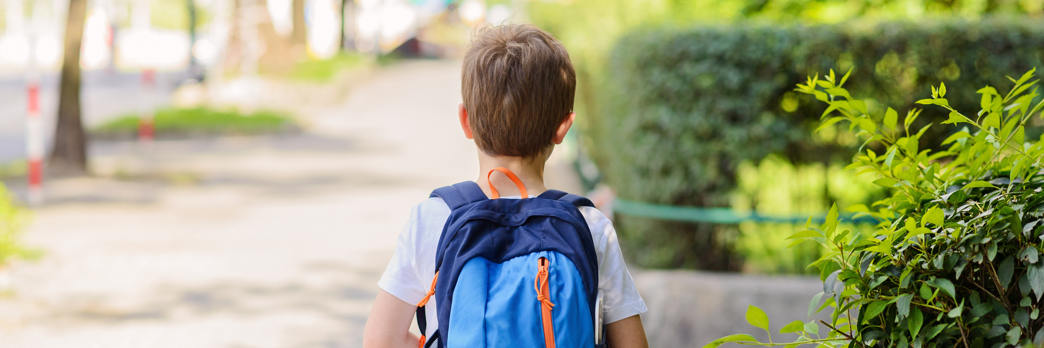 young boy wearing a backpack and walking to school