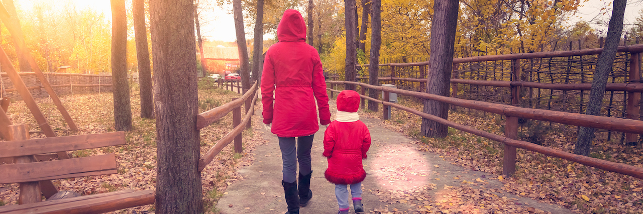 A mom and her daughter walking through a park