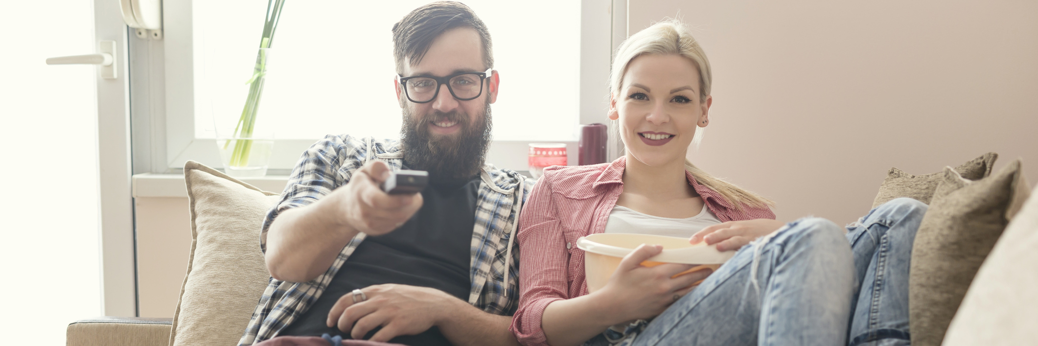 6 Ways You Can Support Your Partner With a Chronic Illness A young couple, popcorn in hand, watching movies.