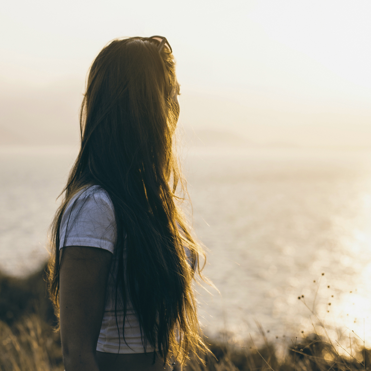 Photo of a young woman look out into the ocean.
