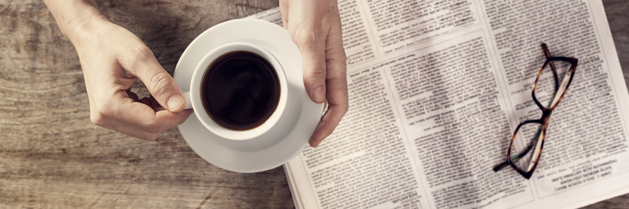 My Husband's Obituary Didn't Mention 'Suicide' Young woman reading newspaper and holding coffee cup