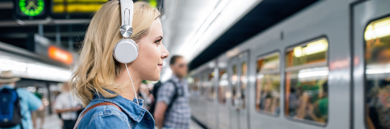 8 Songs I Connect to as Someone With PTSD A woman with her earphones in waiting for a subway