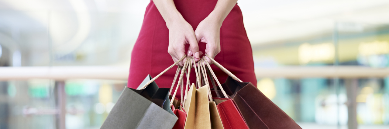 What Going Shopping Meant to Me in Anorexia Recovery young woman female shopper standing with colorful paper bags in hands in shopping mall or department store, focus on hands
