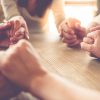 close up image of business team holding hands together on wooden table in warm light