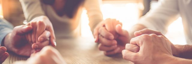 close up image of business team holding hands together on wooden table in warm light