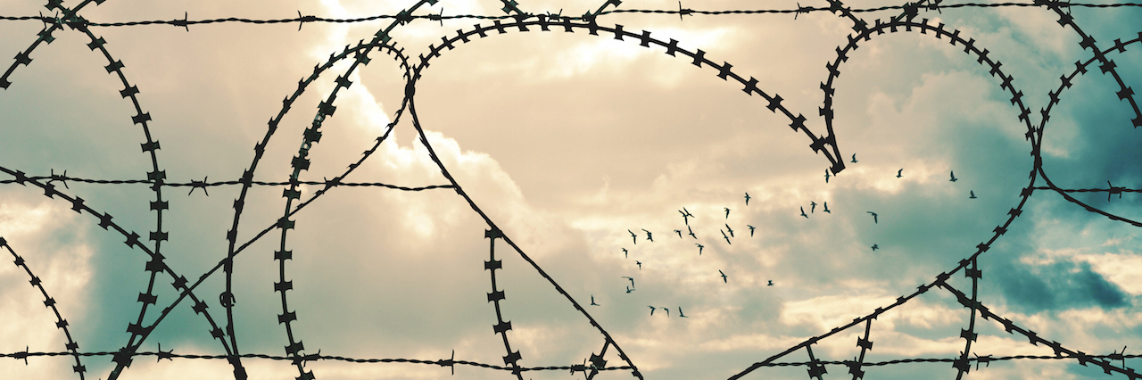 The Dos and Don'ts of Loving Someone With PTSD heart shape in a barbed wire fence against a sky