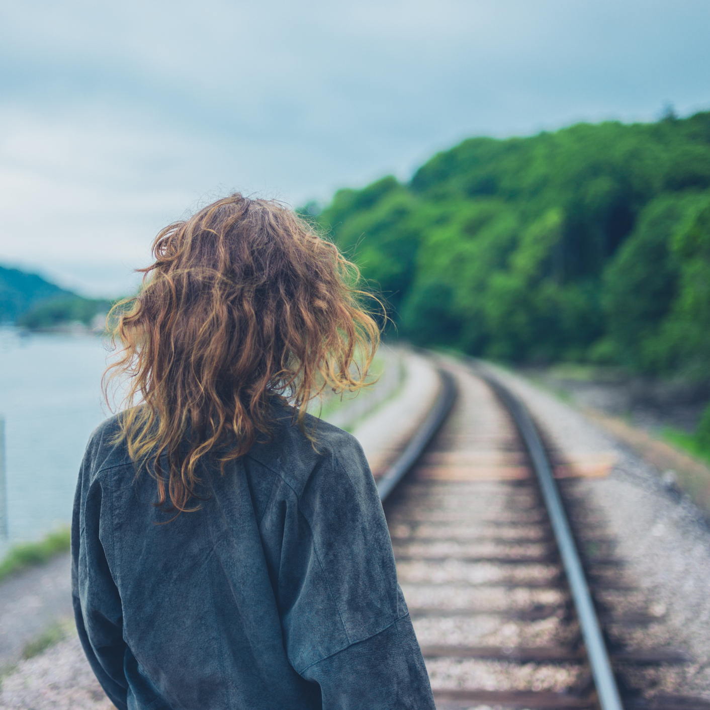 young woman walking along railroad tracks