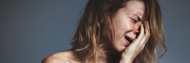 young woman in distress crying on gray background