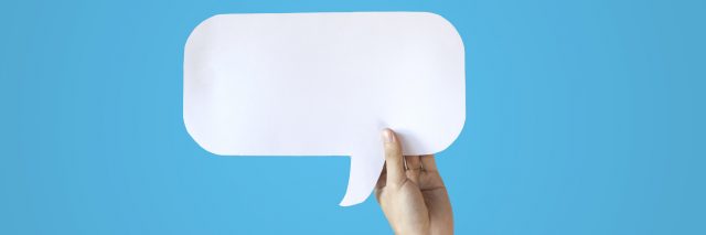 Speech bubble being held in front of blue background.