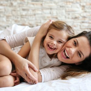 mother and young daughter lying in bed and cuddling