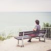 Man sitting on bench overlooking sea.