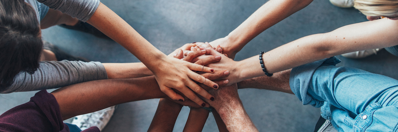 Why Mental Health Advocate's Need to Validate Each Other's Stories Young college students putting their hands on top of each other