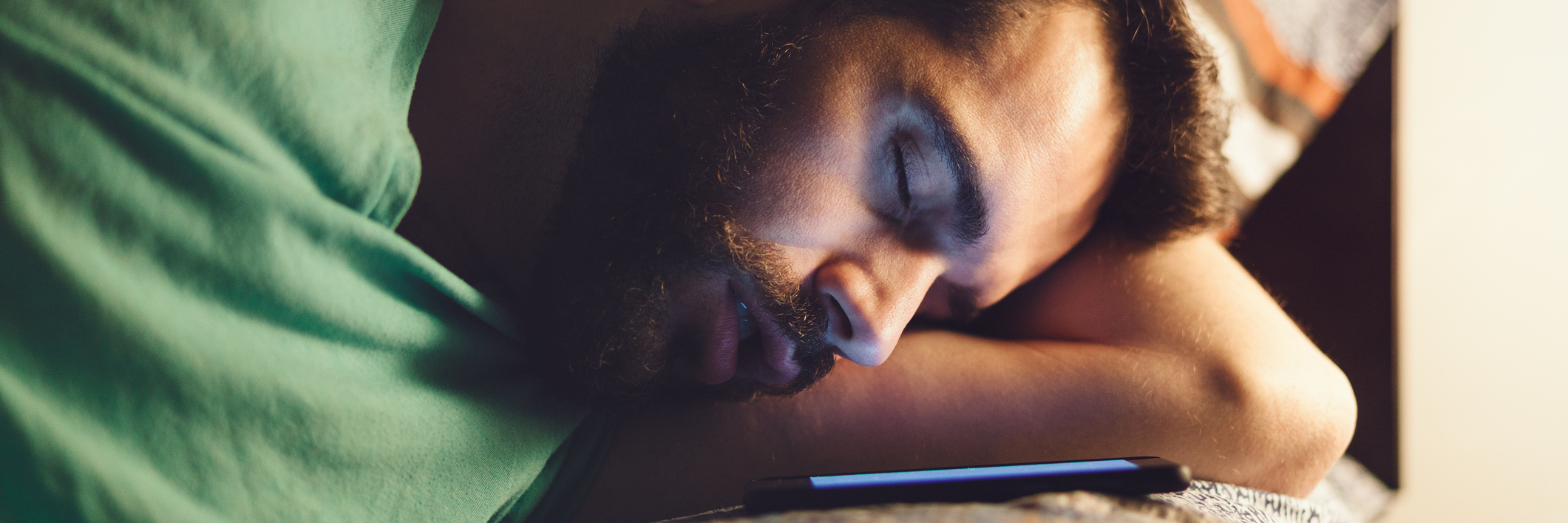 man sleeping with his iphone open on the bed next to him