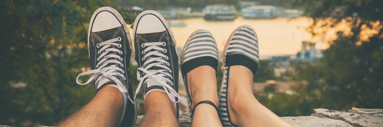 Navigating Romantic Relationships and Social Anxiety A couple sitting by the water, you can only see their feet and legs