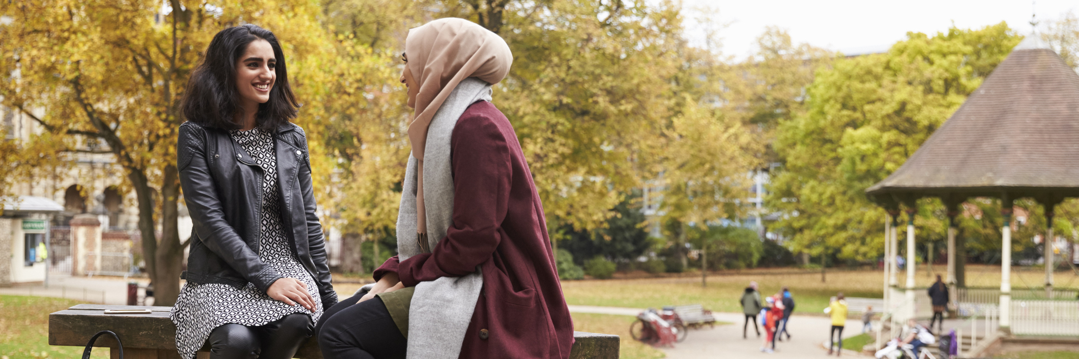 two women talking on a park bench