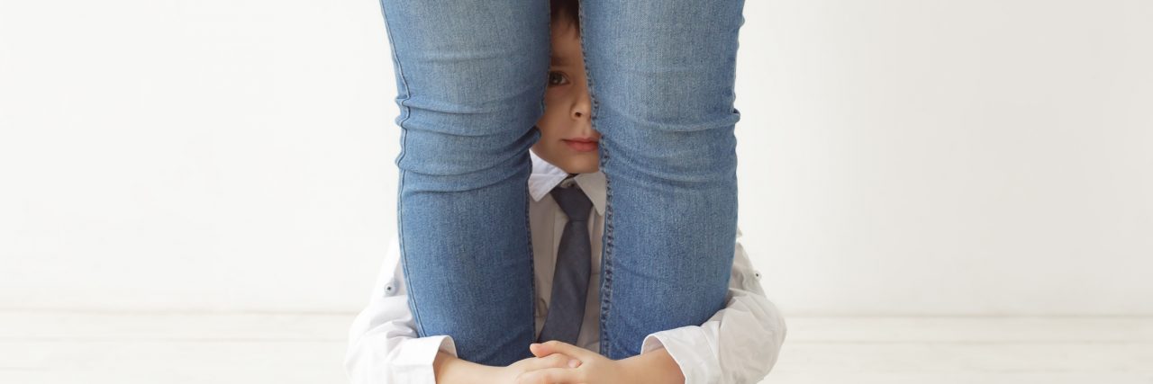 The Strength of a Mom to a Child With a 2p16.3 Microdeletion The boy hugs mom's legs, playing hide and seek.