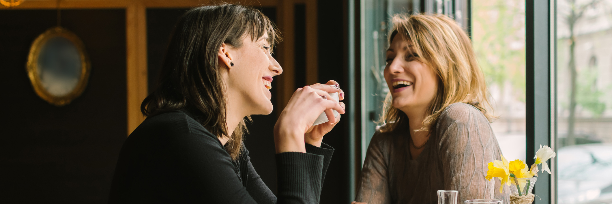 Two female friends sitting at the cafe and talking.