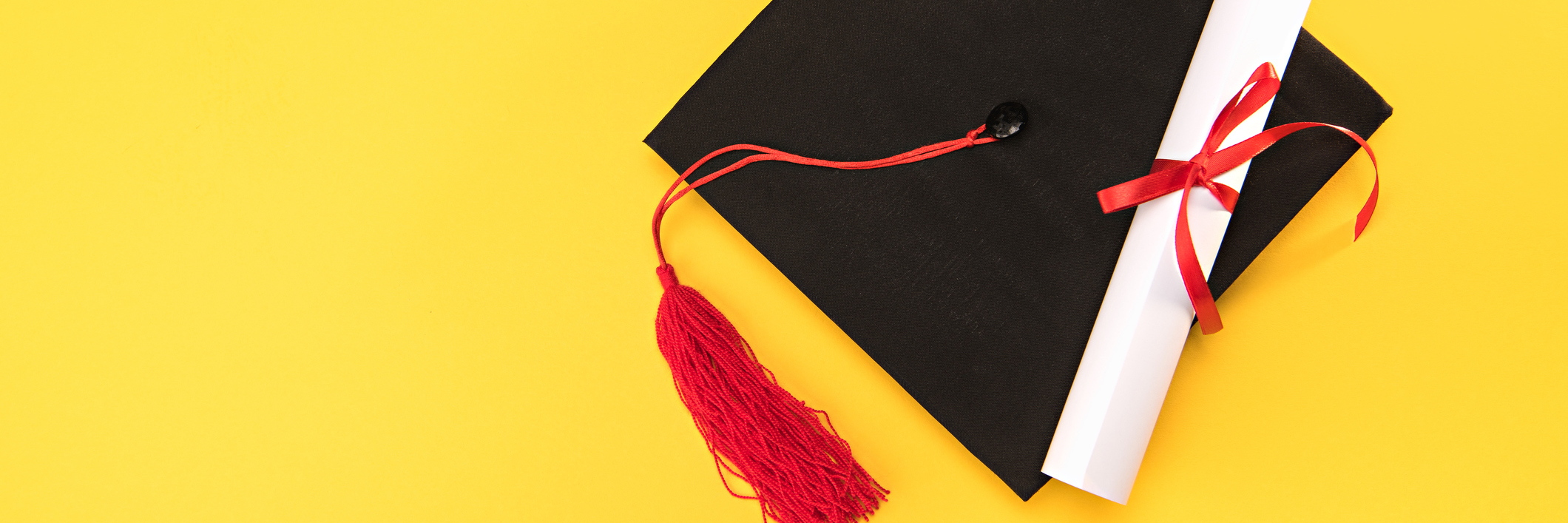 Teen on the Autism Spectrum Excluded From High School Yearbook Top view of graduation mortarboard and diploma on yellow background.
